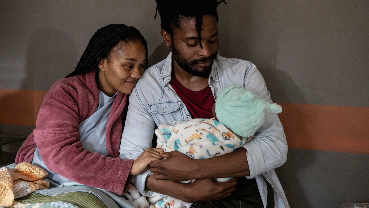 Two African parents holding their newborn baby