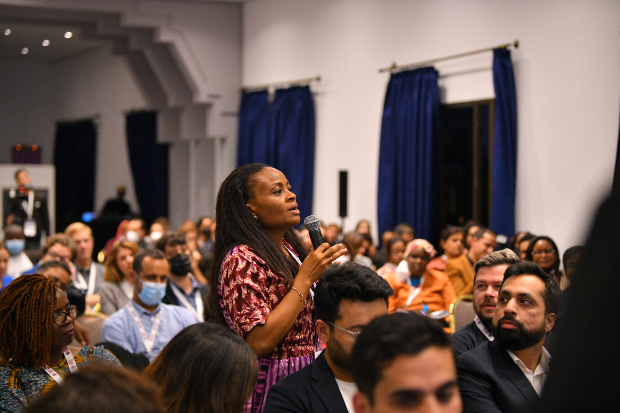 Audience member with a mic standing during an oral presentation during the 2022 international social and behavior change communication Summit